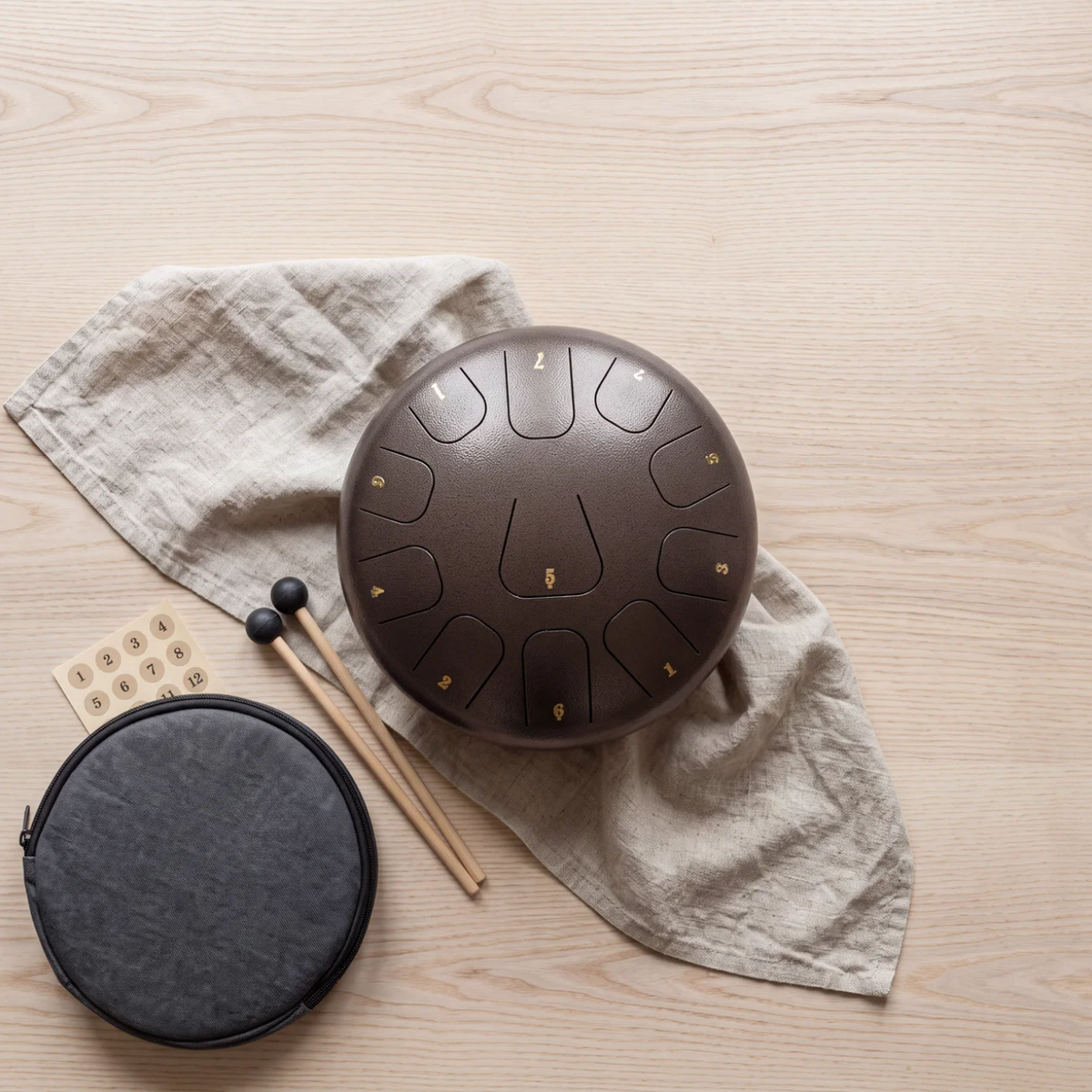 The drum laid out with its mallets, carry bag, note stickers and a linen cloth